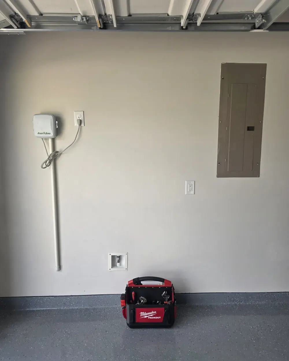 Bare garage wall before the job, with only the capped softener loop stubbed out through the wall plate.